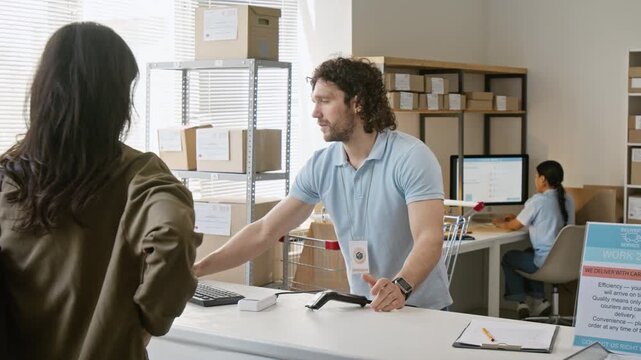 Caucasian young clerk scanning barcode on smartphone and handing cardboard parcel box to female customer. Clip suits e-commerce logistics and delivery service commercials