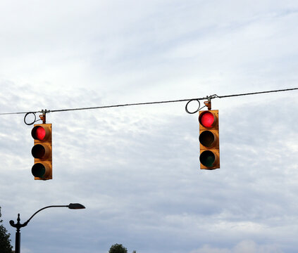 Overhead hanging traffic signals displaying red lights on wire at city intersection