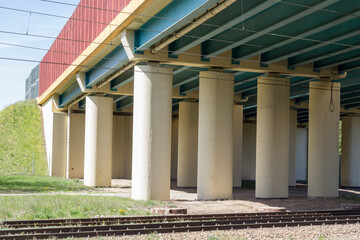 Wiadukt drogowy wsparty na betonowych filarach nad torami kolejowymi, widok konstrukcji infrastruktury transportowej. © Henryk Guziak
