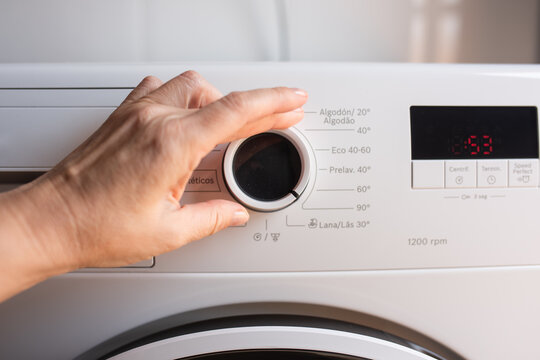 Hand Adjusting Washing Machine Control Dial with Digital Display at Home Laundry