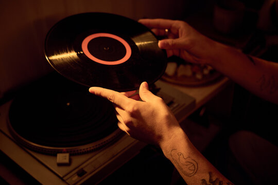 Young Caucasian adult placing vinyl record on turntable player at home. Close up shot suitable for music marketing, retro audio entertainment, lifestyle blogs and hobby content