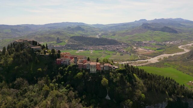 Stunning aerial drone panorama of medieval Montebello Castle perched on a rocky hill surrounded by lush green valley and historic village in Poggio Torriana, Emilia-Romagna, Italy