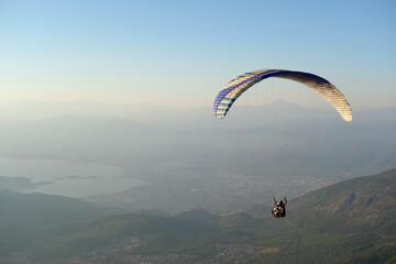 Paraglider flying over mountains and sea coast at sunset © photoguns