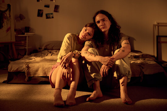 Portrait of young adult Caucasian romantic couple sitting on bedroom floor together. Suitable for relationship counseling, mental wellness, lifestyle advertising
