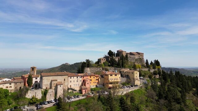 Stunning aerial drone panorama of medieval Montebello Castle perched on a rocky hill surrounded by lush green valley and historic village in Poggio Torriana, Emilia-Romagna, Italy