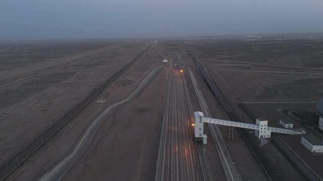 aerial view of railway tracks and train lights in the desert wilderness at dusk