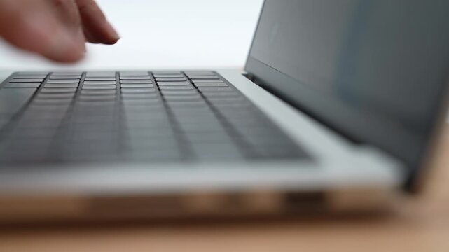 Close-up of a person typing on a laptop keyboard against a clean white background. This high-quality 4K footage captures hands writing, coding, or working remotely, making it perfect for technology
