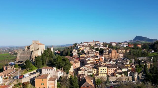 Breathtaking aerial drone view of the medieval Malatesta Fortress in Verucchio overlooking the vast Valmarecchia countryside and Adriatic coast under a clear sky in Emilia-Romagna, Italy