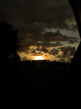 Sol poniente rompiendo a trav&eacute;s de nubes oscuras en un paisaje dram&aacute;tico al atardecer.