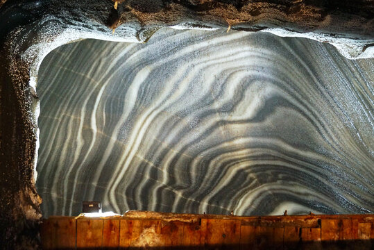 Salt wall inside mine chamber in Salina Turda, revealing wavy geological mineral strata. Captures halite formation, ancient natural rock layers, evaporite geology, and underground geological heritage.
