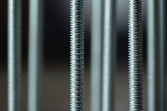 Threaded rods creating a repetitive pattern, representing precision engineering and industrial components