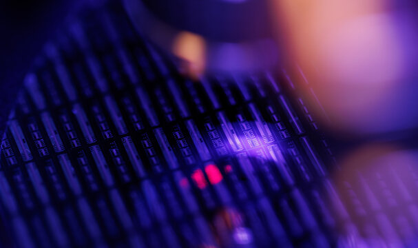 Closeup silicon microchip wafer with purple neon bokeh lighting for technology background and cyberpunk synthwave electronics
