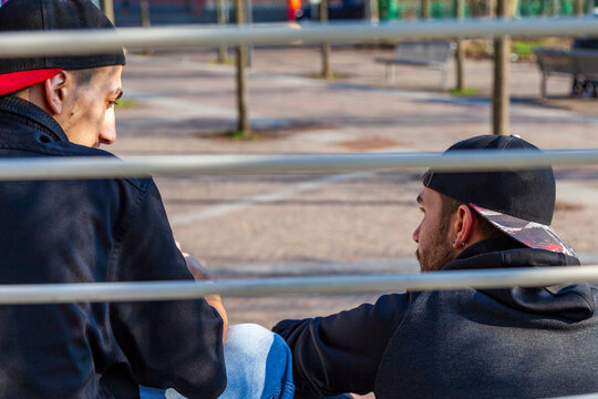 Two young men sitting in a park, communicating outdoors in city park