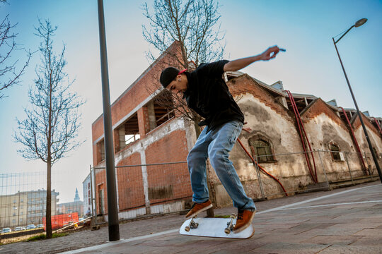 Young man skateboarding on an urban street, performing a jump or trick