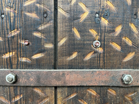 Full frame background texture of old damaged wood planks reinforced with a rusty iron strip, bolts, and screws