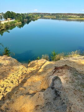 Sandy Slope Overlooking Calm Turquoise Quarry Lake Vertical