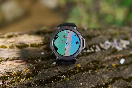 Rugged smartwatch with GPS navigation map lying on a mossy stone outdoors