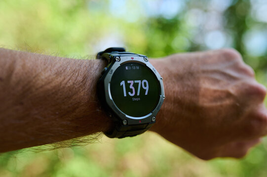 Smartwatch displaying daily step count tracking on a man's wrist outdoors