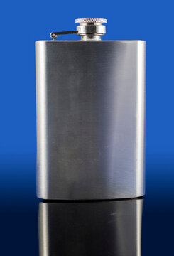 Stainless steel hip flask isolated on dark background with reflection