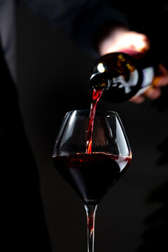 Rich Cabernet Sauvignon red wine in glass &mdash; professional tasting session. Restaurant sommelier with open bottle pouring alcoholic drink. Exclusive catering service, gourmet fine dining event.