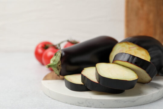 Fresh raw eggplants and tomatoes on light grey table, closeup. Space for text