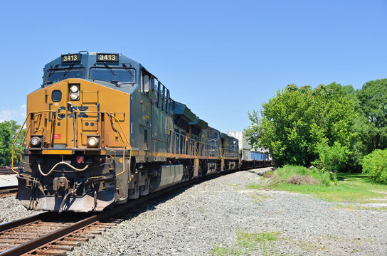 A trio of CSX Transportation locomotives emerge from a curve  while leading an eastbound stack train through south suburban Chicago.