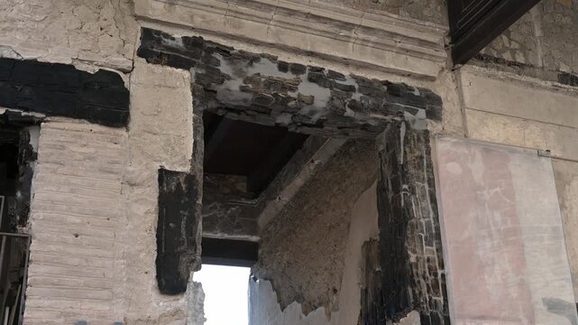 ERCOLANO, ITALY - SEPTEMBER 20, 2026: Carbonized wooden door frame preserved inside an ancient Roman house in Herculaneum, extraordinary evidence of pyroclastic surge preservation from the 79 AD Mount