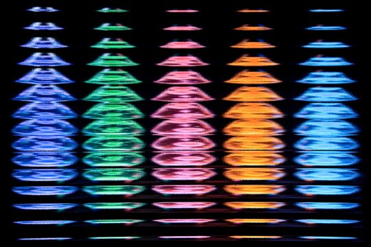 Abstract full frame photo of vibrant rainbow neon light equalizer spectrum columns shining through fluted glass on black background. Concept of sound visualization, audio spectrum, music equalizer, cy