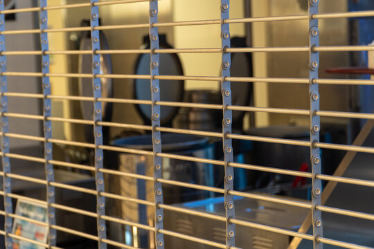 Close-up of a sturdy metal security rolling shutter gate, securely closed over a blurred food stand or business storefront, symbolizing temporary closure, protection, and urban economic challenges.