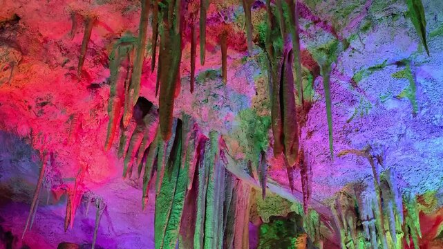 Mystical underground cave with dramatic stalactites and stalagmites. Dripping water illuminated by light.