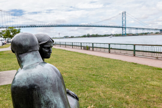 The sculpture Consolation (1997) by Joe Rosenthal faces the Ambassador Bridge, symbol of Detroit-Windsor trade, along the Detroit River waterfront in Windsor Sculpture Park. July 2026