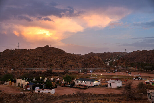 Saudi Arabia Tourism - Scenic sunset sky with golden clouds and storm clouds over Al Taif mountain landscape and desert resort lights, ideal for Saudi National Day and travel campaigns
