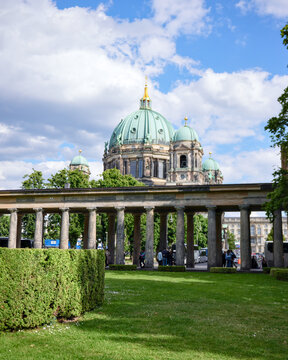 Berlin Cathedral domes framed by Museum Island colonnade and garden