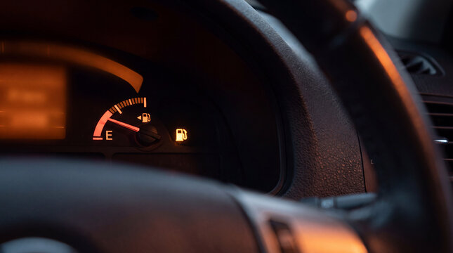 Gauge approaching empty fuel level indicator inside vehicle dashboard displaying anxious mood with low petrol sign showing caution