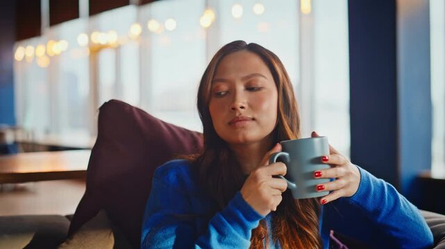 Close up woman drinking tea office lounge. Thoughtful asian girl holding mug.