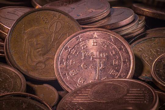 Close up of assorted copper colored coins with embossed symbols, numerals, portraits, and worn surfaces arranged in overlapping layers as a numismatic currency collection