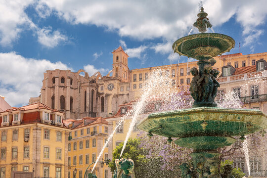 Ornamental fountain with the historic Carmo Convent and traditional buildings in central Lisbon, Portugal.