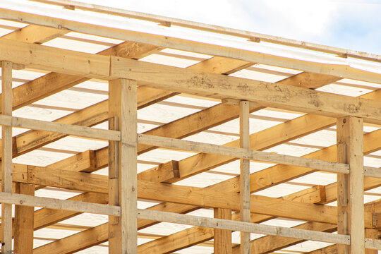 Wooden roof truss. Timber frame construction. Rafter beam structure. House framing detail. Roofing construction site. Wooden beam network. Architectural timber framework. Roof truss system. Building