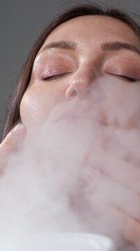 Close up of a woman's face with closed eyes enjoying a relaxing steam treatment from a facial steamer, a professional beauty procedure for moisturizing, cleansing, and improving skin health