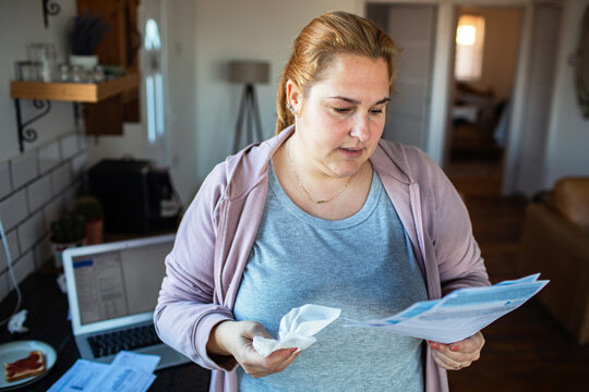 Concerned woman reviewing household bills in home kitchen