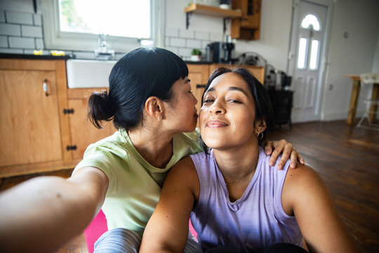 Two women share affectionate selfie in home kitchen