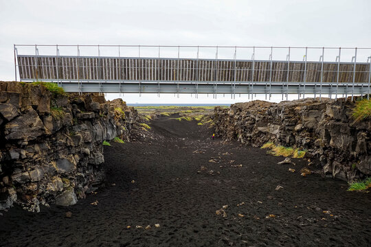 Bridge Between Continents or Lucky Bridge, walkway linking the North American and Eurasian tectonic plates. Rugged lava fields with black sand and poor local vegetation. Reykjanes Peninsula, Iceland.