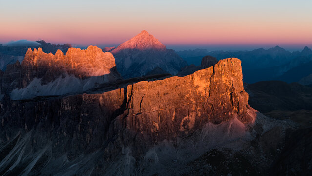 Aerial sunset view of Lastoi de Formin and the Croda da Lago mountain group glowing in warm alpenglow above the alpine landscape near Passo Giau in the Italian Dolomites.