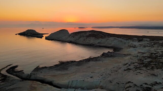 Early morning sunlight during a beautiful sunrise over the Aegean sea seen from the shore of Mandrakia on the Greek island Milos in Greece. Unique landscape on the coastline, natural blue ocean water