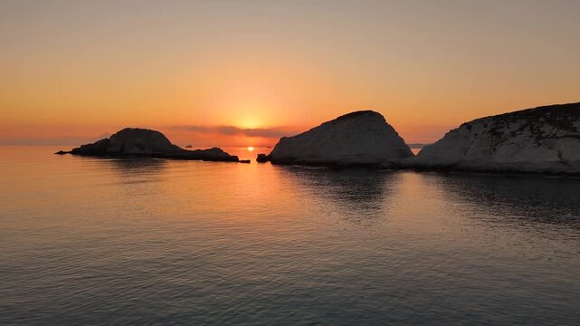 Early morning sunlight during a beautiful sunrise over the Aegean sea seen from the shore of Mandrakia on the Greek island Milos in Greece. Unique landscape on the coastline, natural blue ocean water