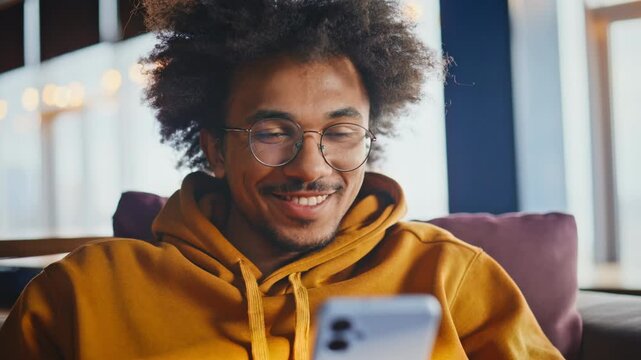Young man texting phone lounge sofa. Closeup hands scrolling smartphone break.