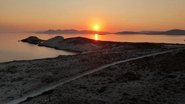 Early morning sunlight during a beautiful sunrise over the Aegean sea seen from the shore of Mandrakia on the Greek island Milos in Greece. Unique landscape on the coastline, natural blue ocean water