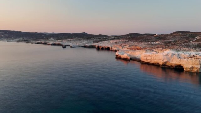 Early morning sunlight during a beautiful sunrise over the Aegean sea seen from the shore of Mandrakia on the Greek island Milos in Greece. Unique landscape on the coastline, natural blue ocean water