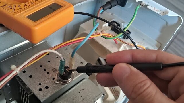 Technician testing home appliance thermal fuse using digital multimeter