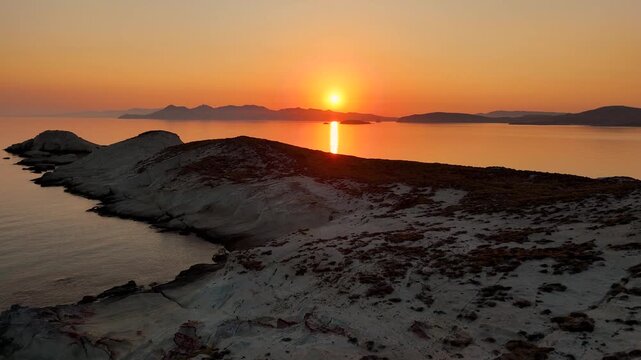 Early morning sunlight during a beautiful sunrise over the Aegean sea seen from the shore of Mandrakia on the Greek island Milos in Greece. Unique landscape on the coastline, natural blue ocean water